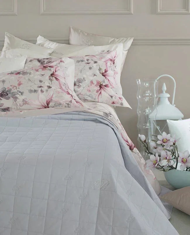Camera elegante con biancheria da letto di lusso Made in Italy, copriletto grigio e cuscini con motivi floreali rosa